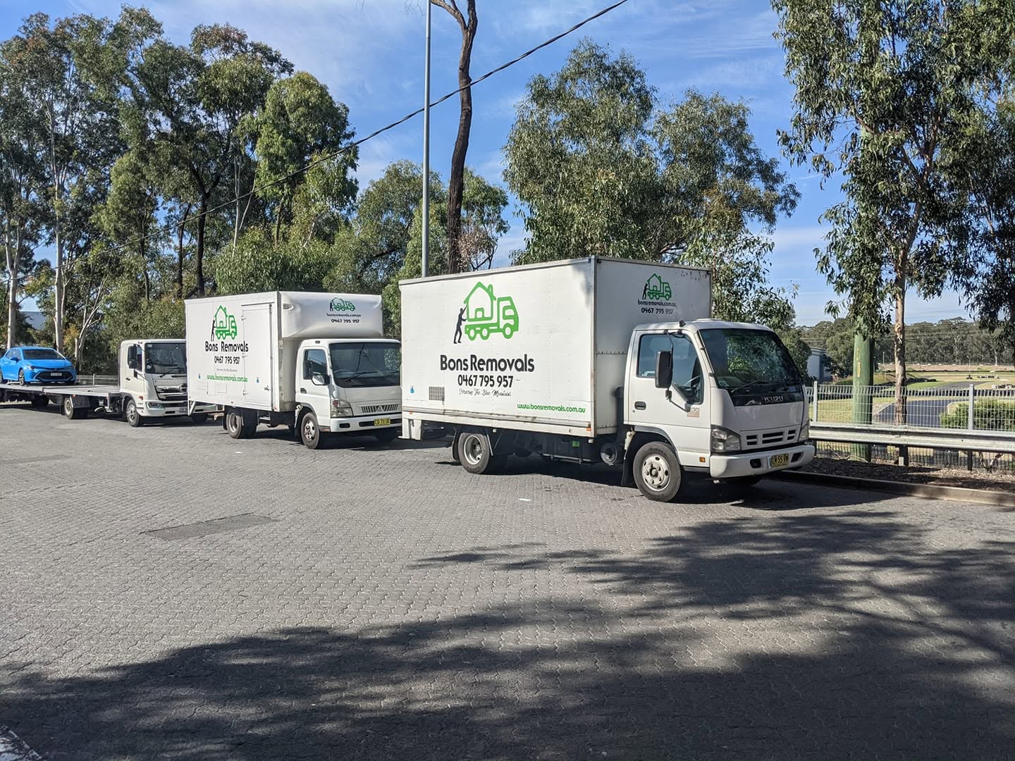 The Bons Removals trucks lined up together in a car park among gum trees