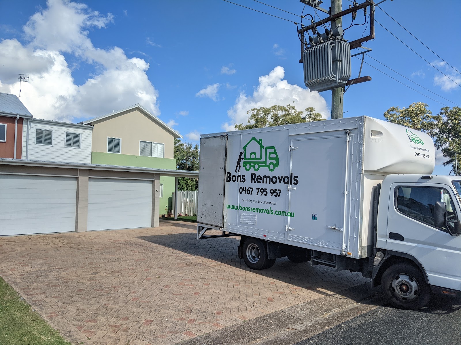 Bons Removals truck parked in a driveway in front of townhouse garages