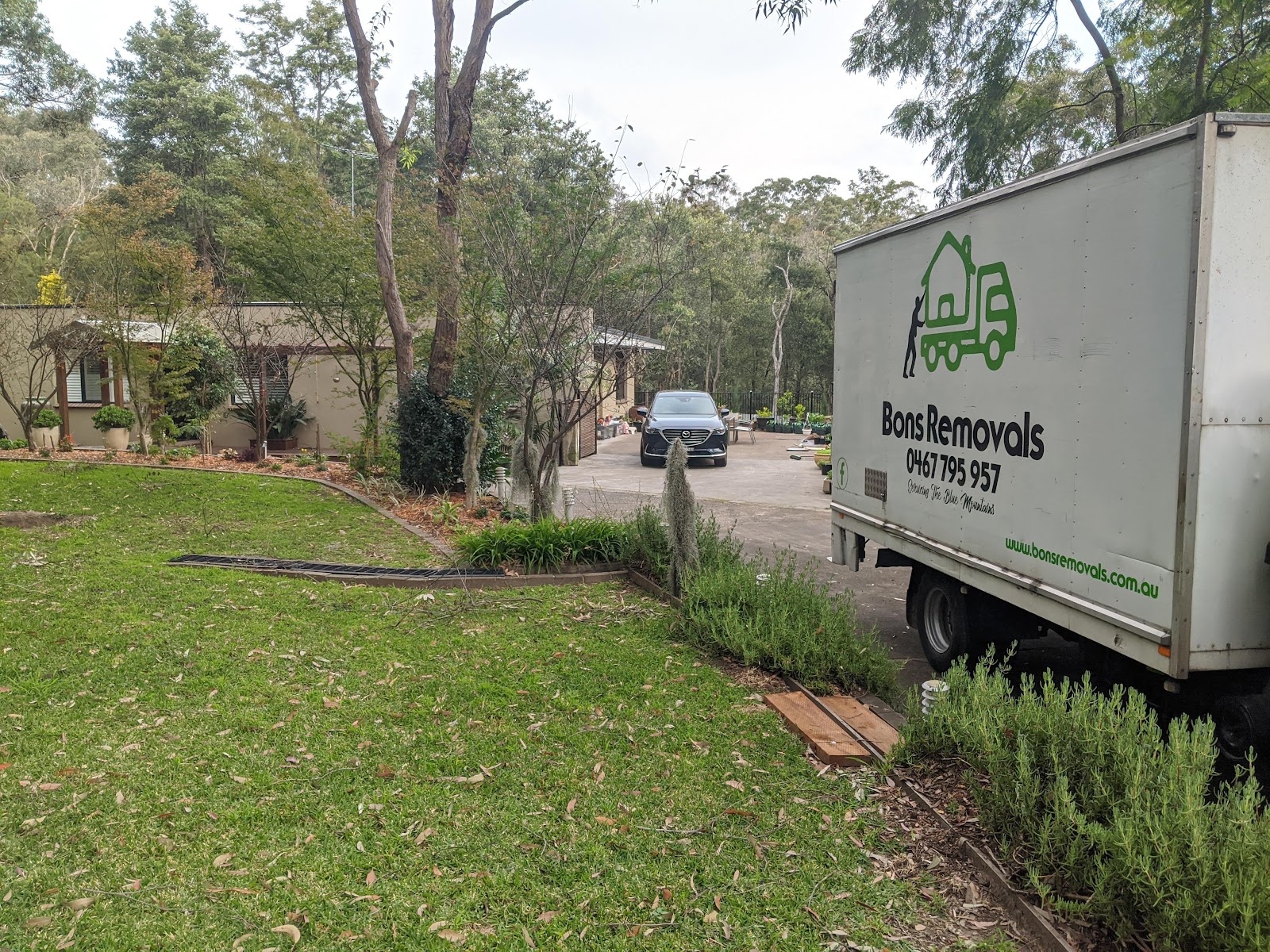 Bons Removals truck pulled up beside a lawn in a bushy street