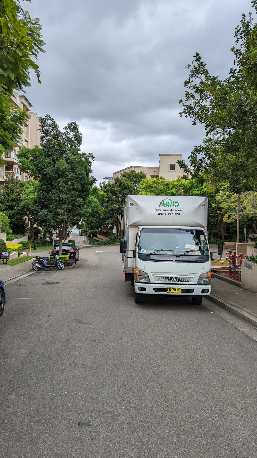 A Bons Removals truck coming down a leafy suburban street